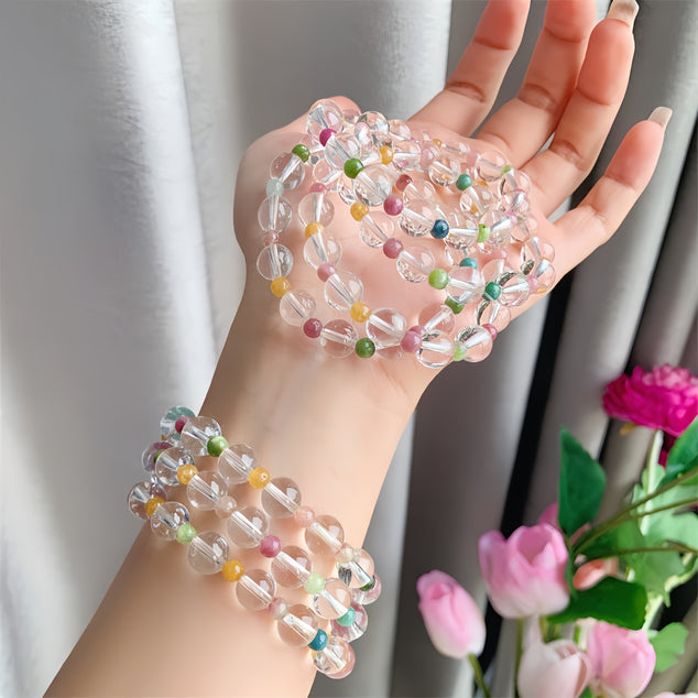 Hand displaying a rainbow tourmaline quartz bracelet, symbolizing healing and color diversity.