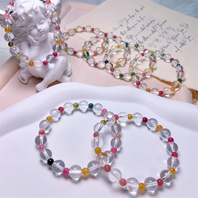 Rainbow tourmaline quartz bracelets alongside a white angel statue, enhancing their spiritual appeal.
