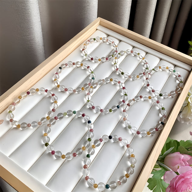 A collection of rainbow tourmaline quartz bracelets neatly arranged in a display box.